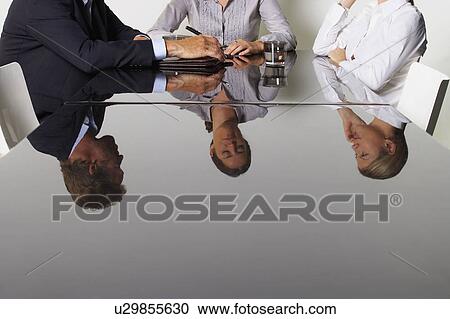 Stock Image - Three business people's reflection in a table.. Fotosearch