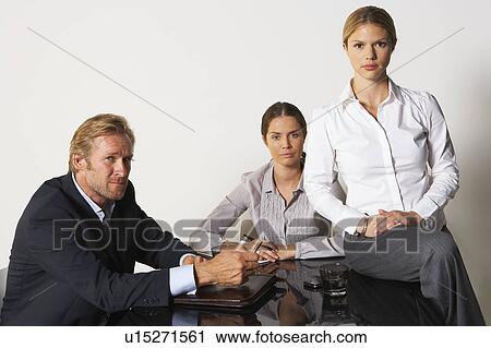 Stock Image - Three businesspeople at a table.. Fotosearch
