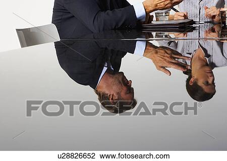 Stock Image - Two business people's reflection in a table.. Fotosearch