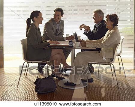 Stock Image - Two businessmen and two businesswomen having meeting in café, shot through window. Alicante, Spain.. Fotosearch