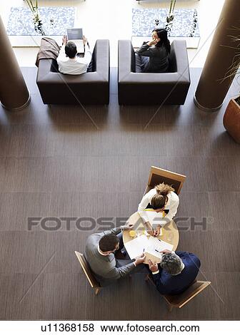 Two businessmen and woman having meeting, overhead view View Large Photo Image Stock Photo - Two businessmen and woman having meeting, overhead view. Fotosearch