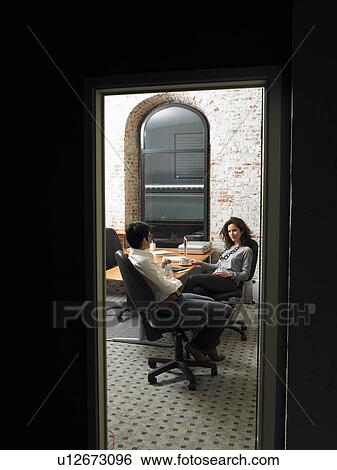 Stock Photograph - Two businesswomen having a meeting, seen through a threshold. Brussels, Belgium.. Fotosearch