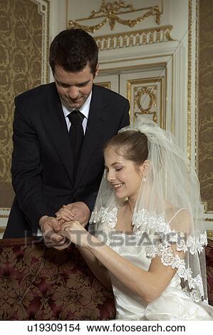 Bride and groom looking at wedding ring View Large Photo Image Picture - Bride and groom looking at wedding ring. Fotosearch