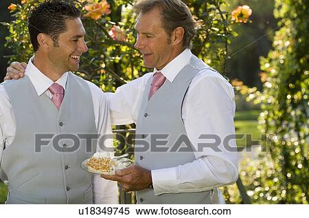 Stock Photography - Mature father and groom talking in garden, smiling. Fotosearch
