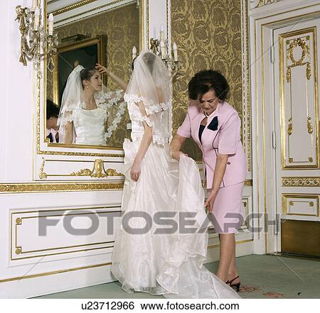 Stock Photograph - Mother adjusting wedding dress on bride. Fotosearch