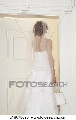 Stock Photograph - young bride standing in doorway, rear view. Fotosearch