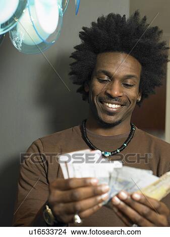 Picture - Man counting banknotes, smiling. Fotosearch