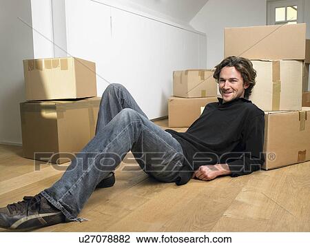 Man lying on floor smiling with moving boxes around him. View Large Photo Image Stock Image - Man lying on floor smiling with moving boxes around him.. Fotosearch