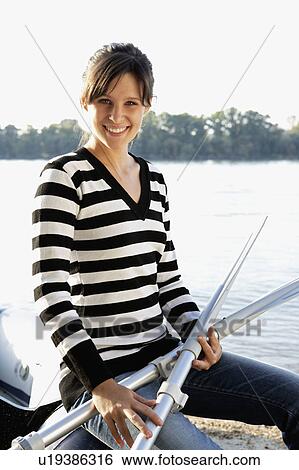 Woman leaning on a raft holding two oars smiling. View Large Photo Image Stock Photograph - Woman leaning on a raft holding two oars smiling.. Fotosearch