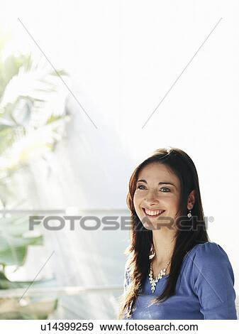 Stock Photo - Woman standing by window, smiling. Fotosearch