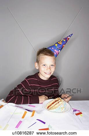 Stock Photo - Boy (8-10) with slice of birthday cake. Fotosearch