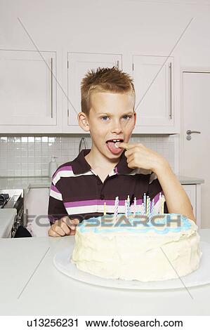 Stock Image - Boy licking cake icing. Fotosearch