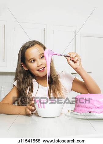Stock Photo - Girl (8-10) decorating cake with icing. Fotosearch