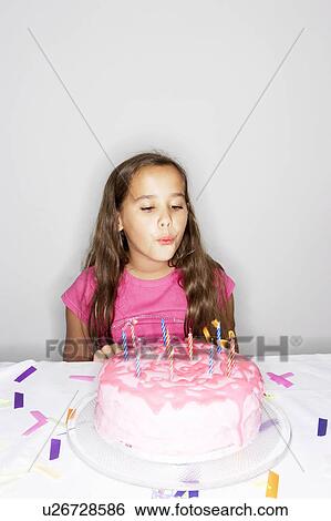 Stock Photograph - Girl blowing out candles on cake. Fotosearch