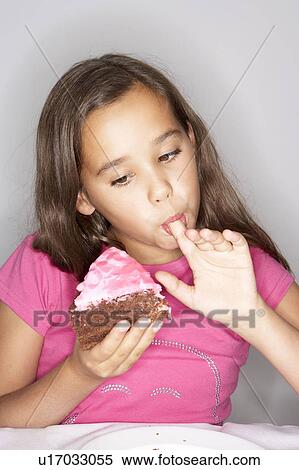 Stock Photography - Girl eating slice of cake. Fotosearch