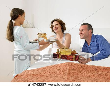 Stock Photo - Girl giving parents breakfast in bed. Fotosearch