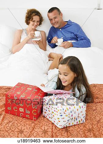Stock Image - Girl on bed, looking at birthday card. Fotosearch