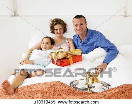 Stock Photography - Girl on bed with mother and father. Fotosearch