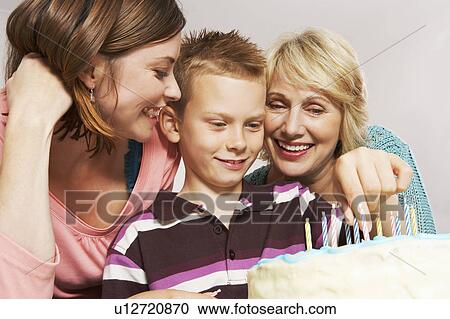 Stock Image - Grandmother, boy and mom decorating cake. Fotosearch