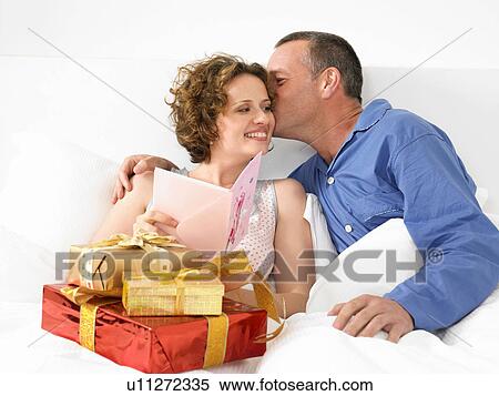 Stock Photography - Man kissing woman in bed. Fotosearch