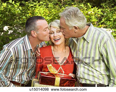Stock Photo - Mature woman being kissed by two men. Fotosearch