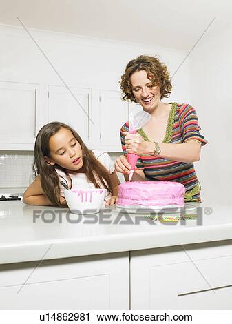 Mother and daughter icing cake View Large Photo Image Stock Image - Mother and daughter icing cake. Fotosearch