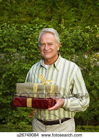 Picture - Senior man holding presents. Fotosearch