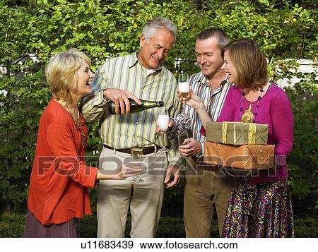 Stock Photo - Senior man pouring Champagne for friends. Fotosearch