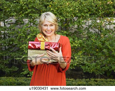 Stock Image - Senior woman holding presents. Fotosearch