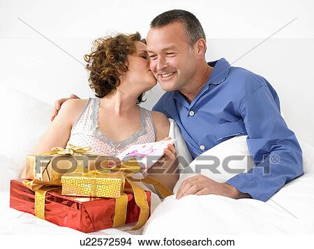 Picture - Woman kissing man in bed. Fotosearch