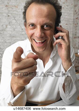 Stock Photograph - Businessman on the phone pointing at camera., Brussels, Belgium.. Fotosearch