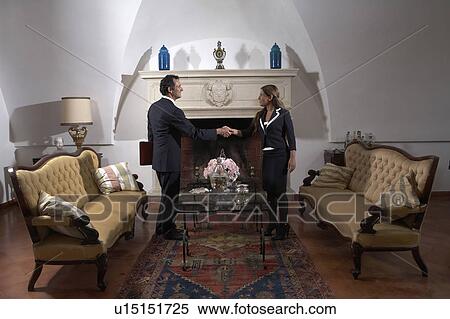 Businessman shaking hands with woman in living room View Large Photo Image Stock Photography - Businessman shaking hands with woman in living room. Fotosearch