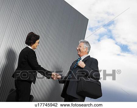 Stock Image - Businesspeople by a silver wall.. Fotosearch