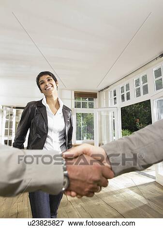 Close up of shaking hands with smiling woman in background. View Large Photo Image Stock Photo - Close up of shaking hands with smiling woman in background.. Fotosearch