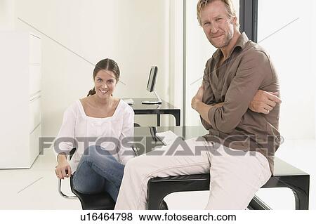 Man and woman in office man sitting on desk. View Large Photo Image Stock Photo - Man and woman in office man sitting on desk.. Fotosearch
