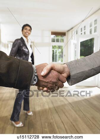 Shake hands in front of smiling woman in an empty house. Close up. View Large Photo Image Stock Photo - Shake hands in front of smiling woman in an empty house. Close up.. Fotosearch
