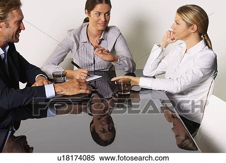 Three businesspeople at a table smiling. View Large Photo Image Stock Photography - Three businesspeople at a table smiling.. Fotosearch