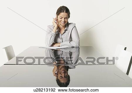 Stock Image - Young business woman at desk with reflections.. Fotosearch