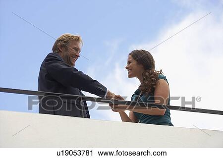 Stock Image - Young businessman and business woman on balcony.. Fotosearch