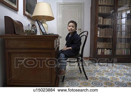 Picture - Boy (4-6) sitting at desk using laptop, portrait. Fotosearch
