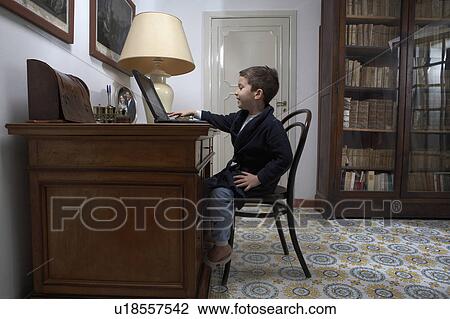 Boy (4-6) sitting at desk using laptop View Large Photo Image Stock Image - Boy (4-6) sitting at desk using laptop. Fotosearch