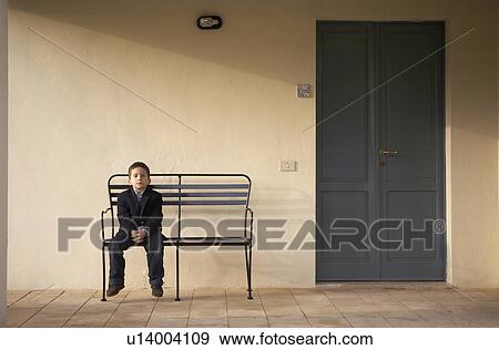 Boy (4-6) sitting on bench outdoors, portrait View Large Photo Image Stock Photo - Boy (4-6) sitting on bench outdoors, portrait. Fotosearch