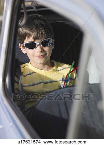 Boy (8-10) in sunglasses sitting in backseat of car with drink, smiling, portrait View Large Photo Image Picture - Boy (8-10) in sunglasses sitting in backseat of car with drink, smiling, portrait. Fotosearch