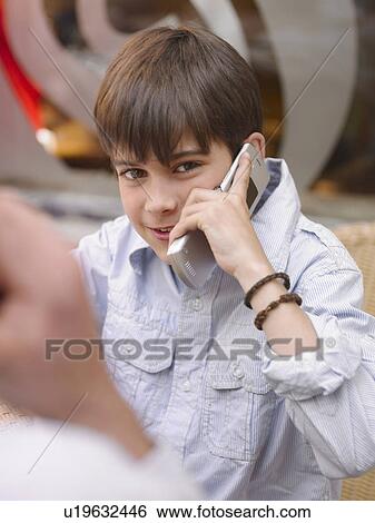 Boy (8-10) sitting at café table, using mobile phone, portrait (differential focus) View Large Photo Image Stock Photograph - Boy (8-10) sitting at café table, using mobile phone, portrait (differential focus). Fotosearch