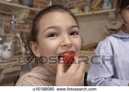 Stock Image - Girl (5-7) eating tomato, close-up, portrait. Fotosearch