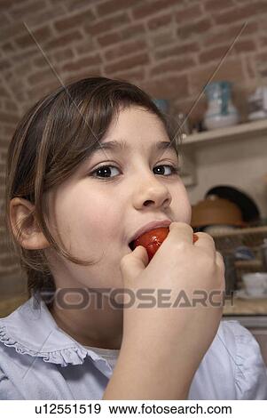 Girl (6-8) eating tomato, close-up, portrait View Large Photo Image Stock Photo - Girl (6-8) eating tomato, close-up, portrait. Fotosearch