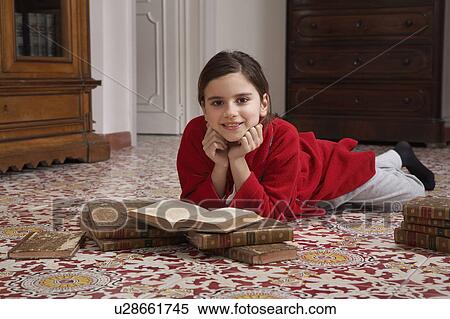 Girl (9-11) lying on floor reading books, portrait View Large Photo Image Stock Photography - Girl (9-11) lying on floor reading books, portrait. Fotosearch