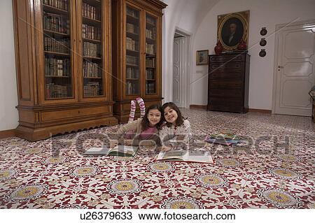 Girls (6-11) lying on floor reading books, smiling, portrait View Large Photo Image Stock Image - Girls (6-11) lying on floor reading books, smiling, portrait. Fotosearch