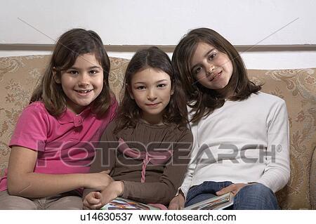 Three girls (5-11) sitting on a sofa, portrait View Large Photo Image Stock Photo - Three girls (5-11) sitting on a sofa, portrait. Fotosearch