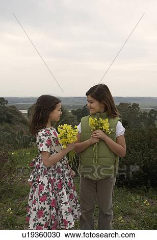 Two girls (5-8) holding bunches of flowers View Large Photo Image Stock Image - Two girls (5-8) holding bunches of flowers. Fotosearch